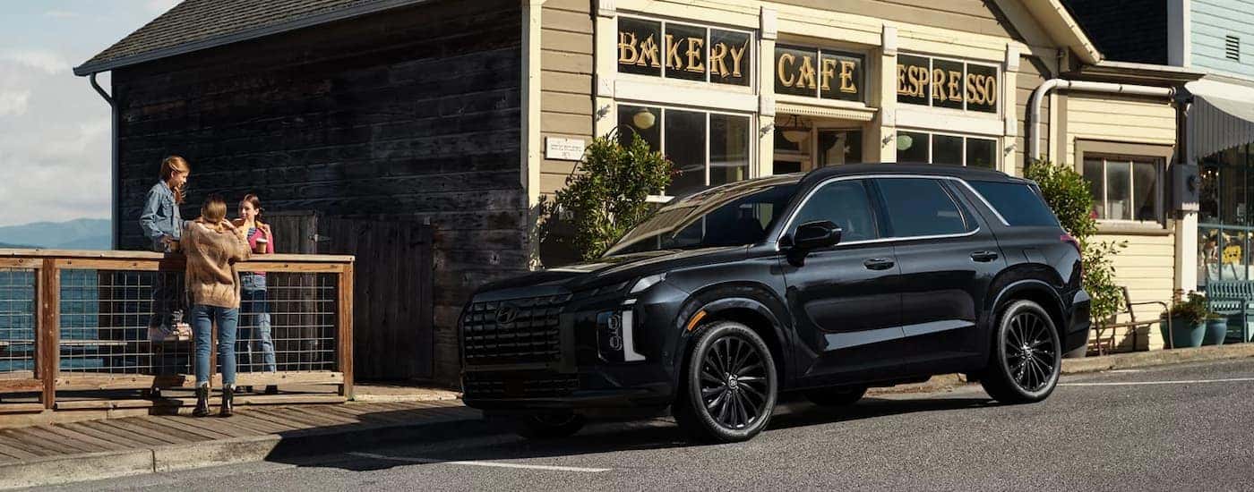 Black 2025 Hyundai Palisade parked on the side of a street near a cafe