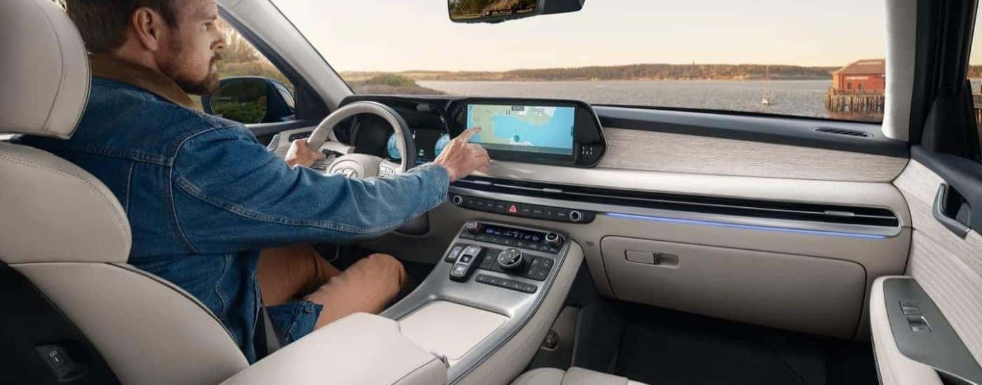 A man using the touch screen infotainment display in a 2023 Hyundai Palisade for sale near The Villages