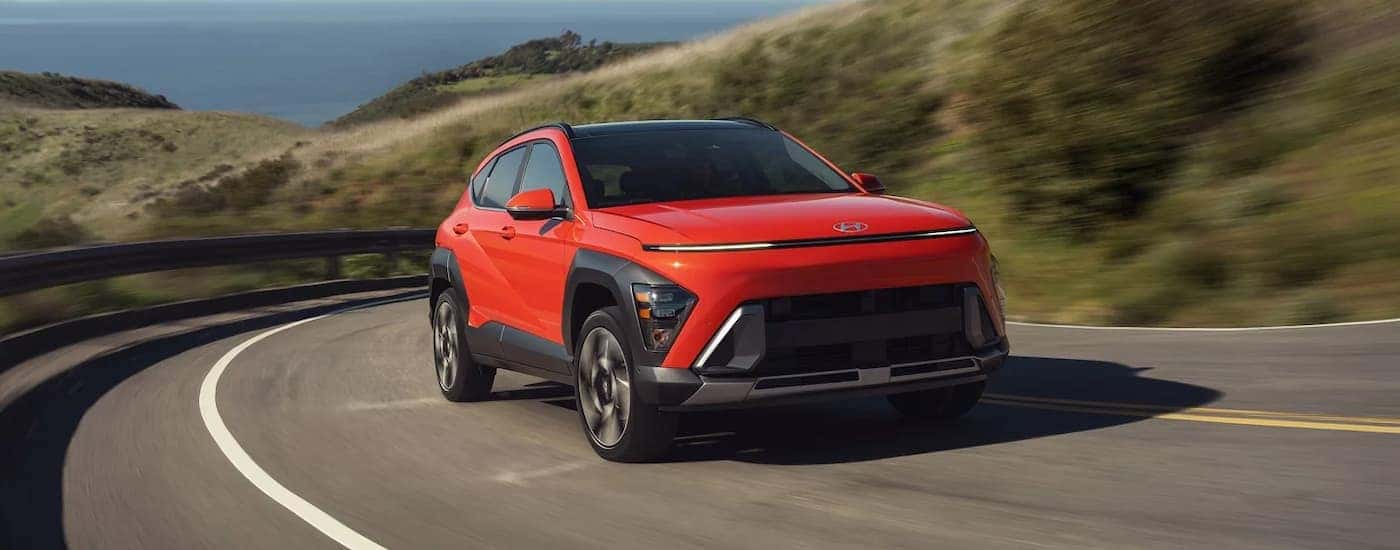 A red 2026 Hyundai Kona driving down a highway