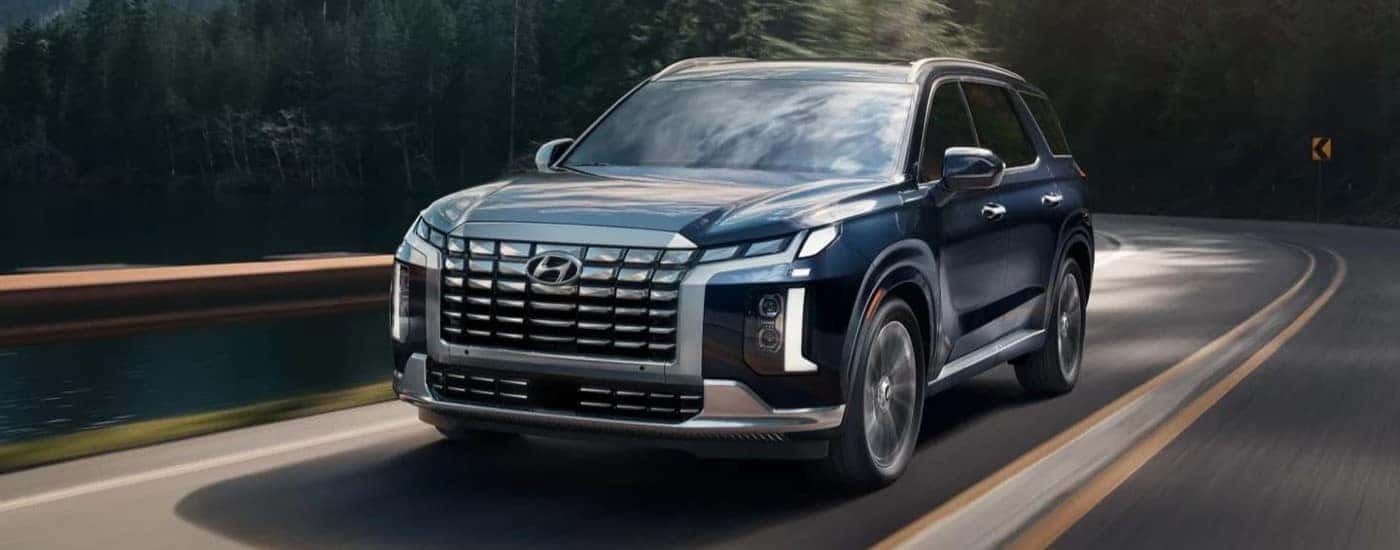 A blue used 2023 Hyundai Palisade for sale in Clermont driving down a road