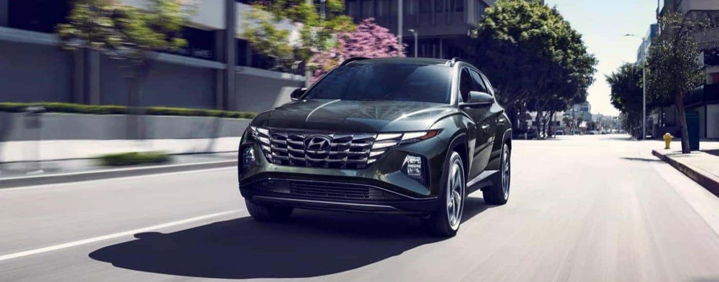 A black 2023 Hyundai Tucson Hybrid Limited driving down a city street