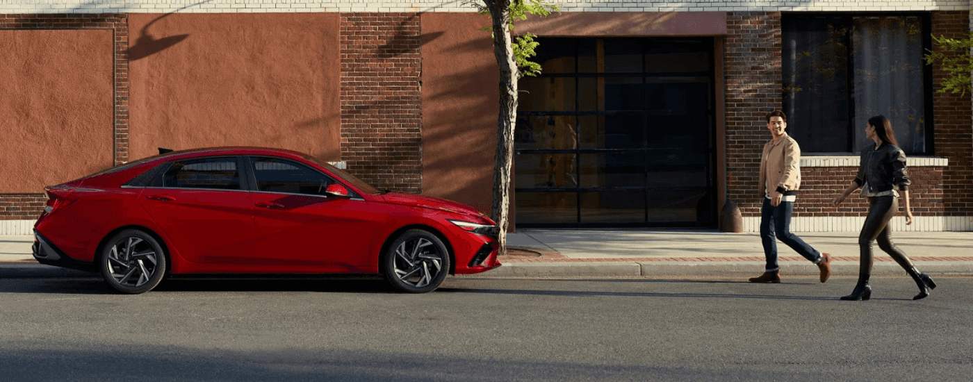 Two people walk up to a red 2026 Hyundai Elantra for sale near the Villages