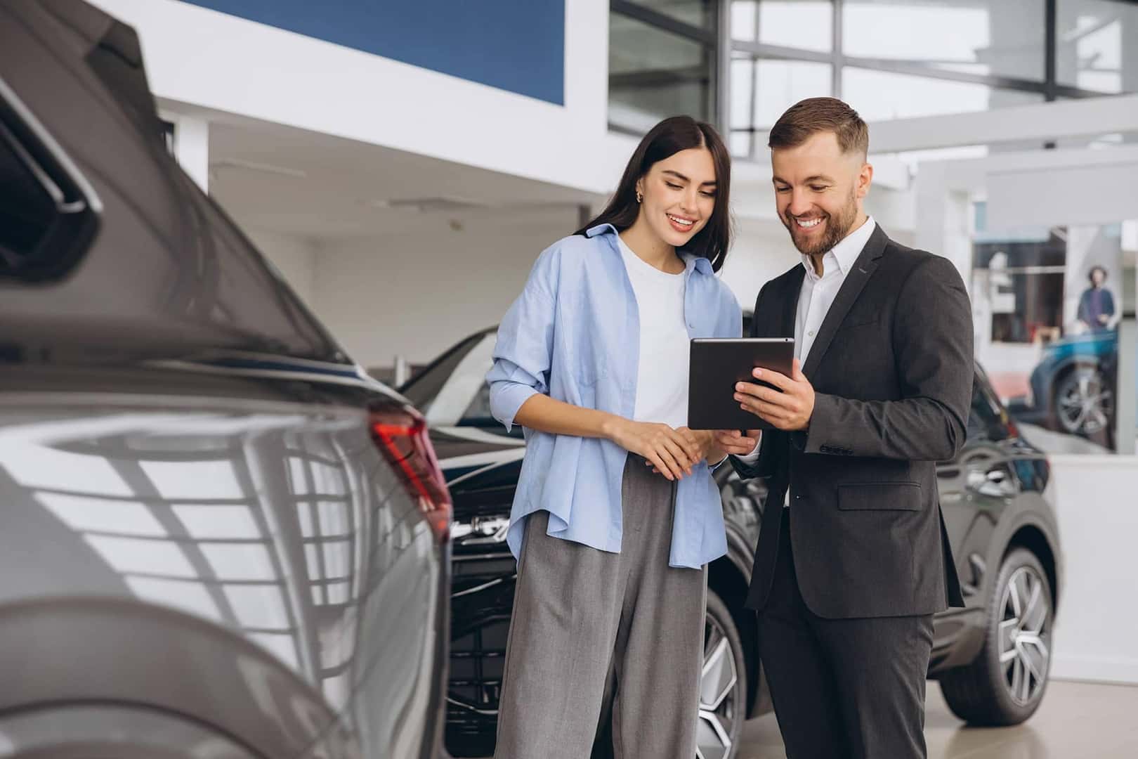 woman at dealership with salesman looking at tablet