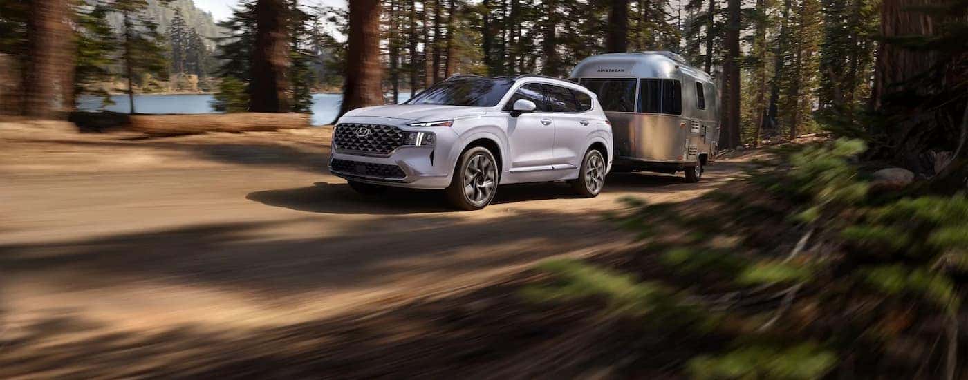 White 2023 Hyundai Santa Fe towing a camper