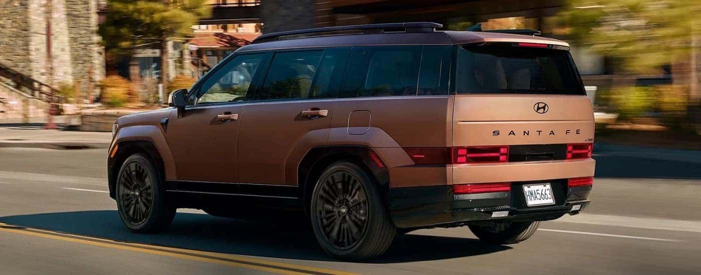 A bronze 2025 Hyundai Santa Fe from the rear at an angle.