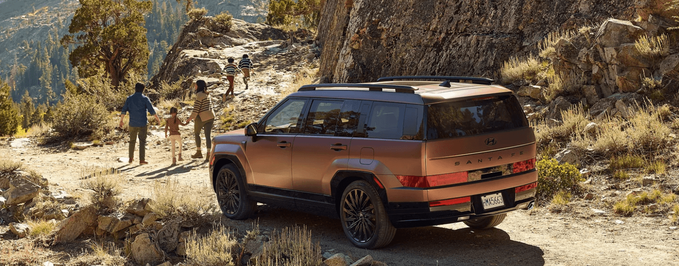 A family hiking away from their brown 2026 Hyundai Santa Fe