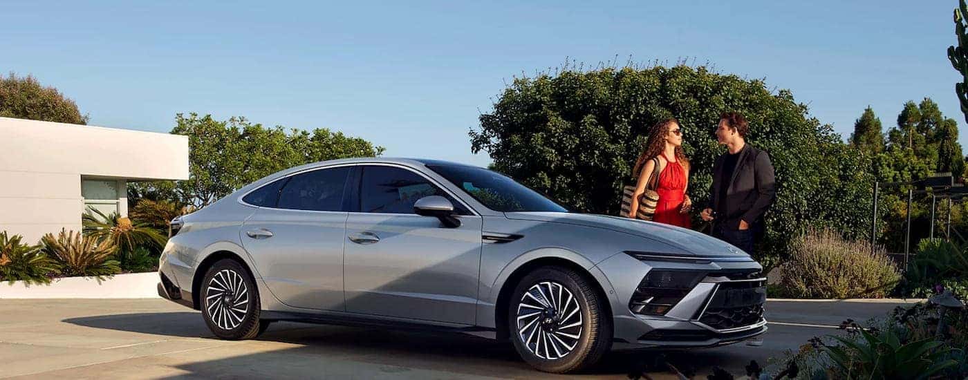 Two people talking near a parked silver 2026 Hyundai Sonata for sale near Orlando.