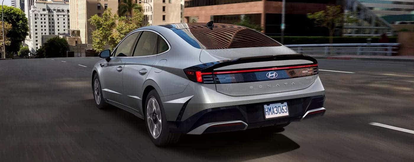 Rear of a silver 2026 Hyundai Sonata driving down a road.