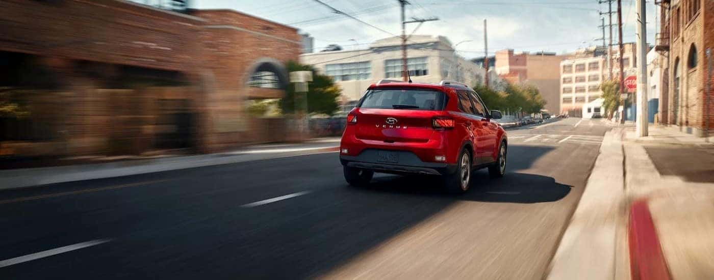 A red 2026 Hyundai Venue driving in a city.