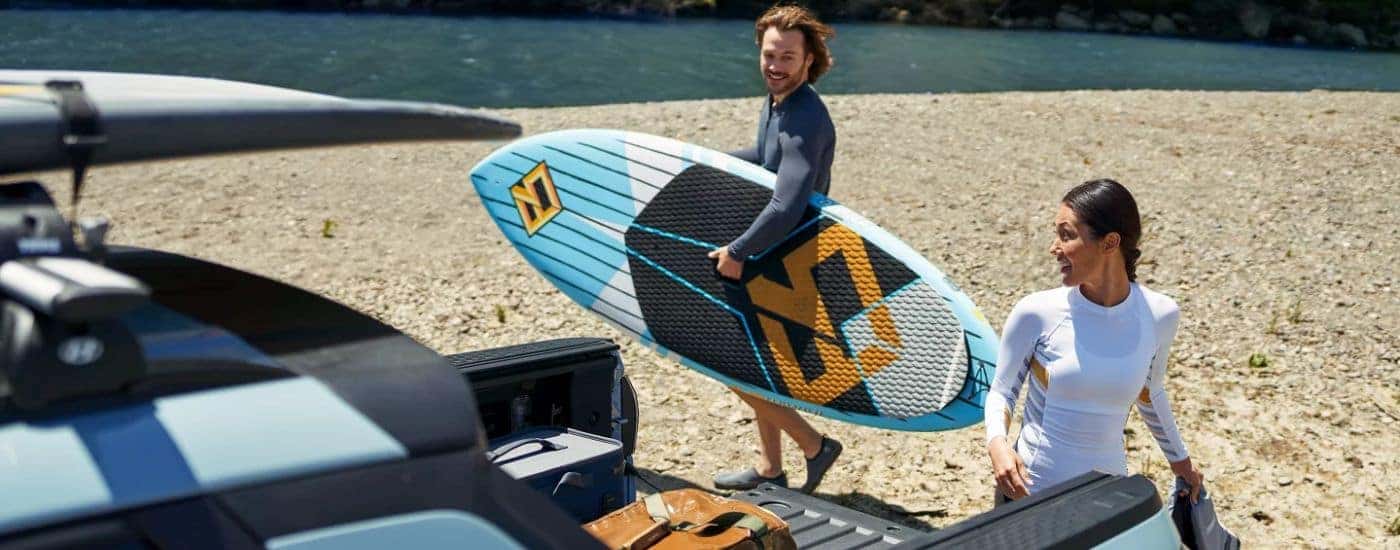 Couple unloading paddleboards from a blue 2026 Hyundai Santa Cruz.