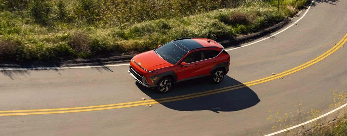Red 2026 Hyundai Kona aerial view driving on a road.
