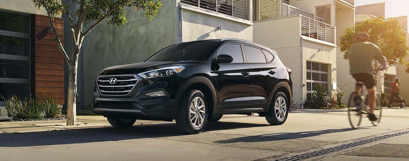Black 2016 Hyundai Tucson parked near a biker