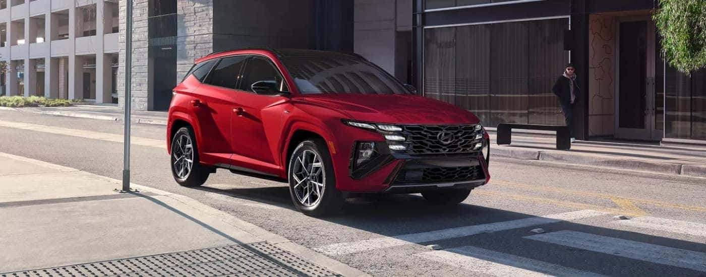 Red 2025 Hyundai Tucson Hybrid parked at a stop sign