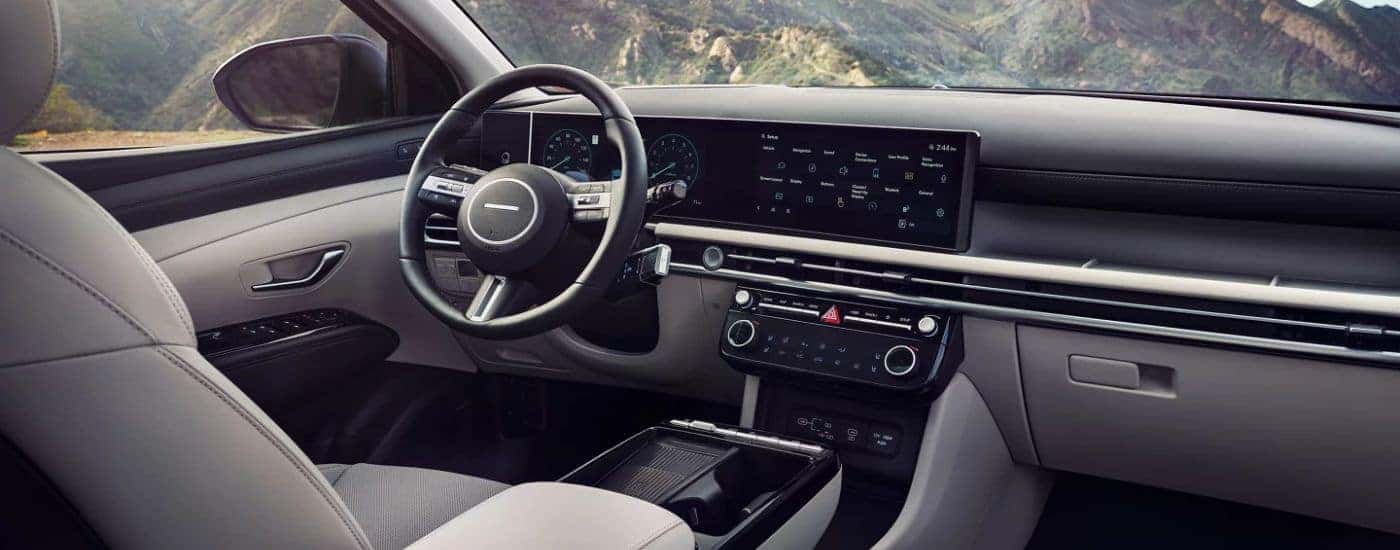 2026 Hyundai Tucson front interior with steering wheel and infotainment display.