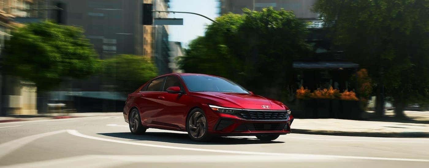 A red 2025 Hyundai Elantra driving in a city.