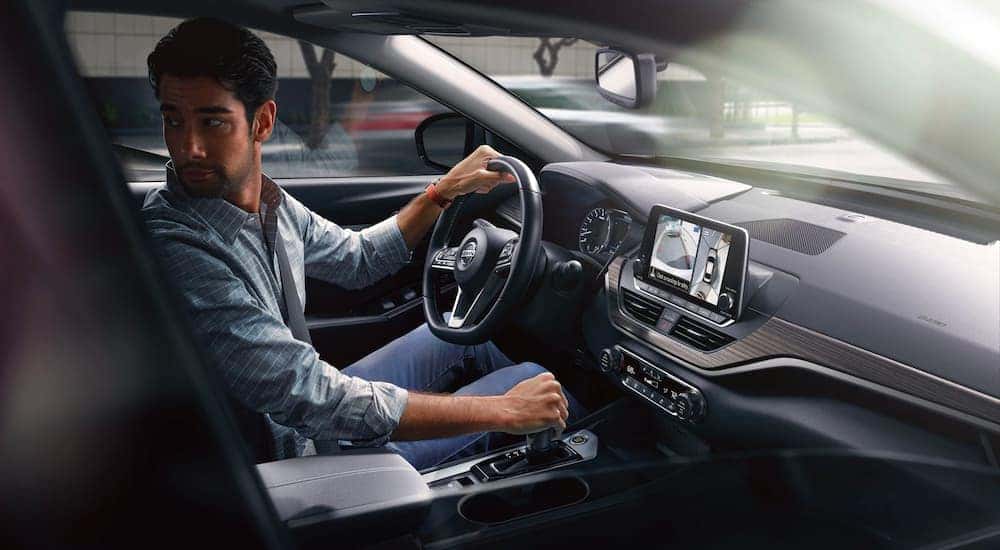 A person is shown looking over their shoulder while reversing in a 2021 Nissan Altima.