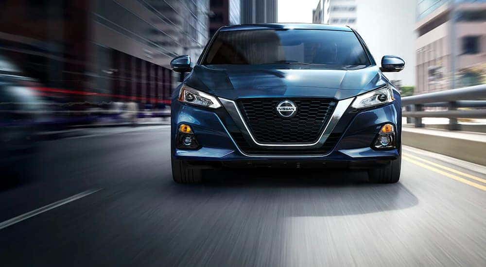 A blue 2021 Nissan Altima is shown from the front driving down a city street after leaving an Illinois Nissan dealer.