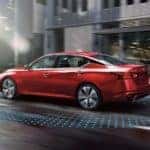 A red 2021 Nissan Altima is on a city street with simulated Safety Shield marking on the ground after leaving a Nissan dealer near me.