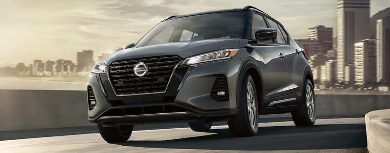 A silver 2021 Nissan Kicks is driving through a city.