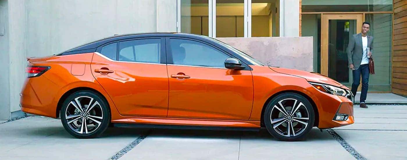 Orange 2021 Nissan Sentra is shown from the side parked against a house