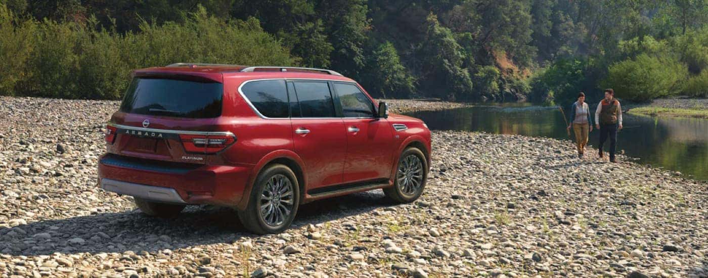 A red 2022 Nissan Armada is shown from the side parked next to a stream.