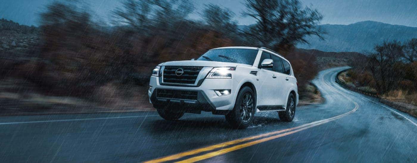 A white 2022 Nissan Armada is shown from the front driving on an open road in the rain after winning a 2022 Nissan Armada vs 2022 Ford Expedition comparison.