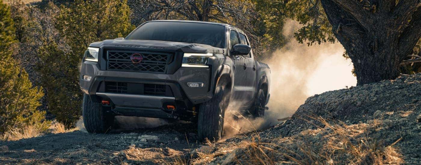 A grey 2022 Nissan Frontier is shown from the front off-roading in the mountains during a 2022 Nissan Frontier vs 2022 Chevy Colorado comparison.