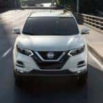 A white 2020 Nissan Rogue Sport is shown from the front driving over a bridge.
