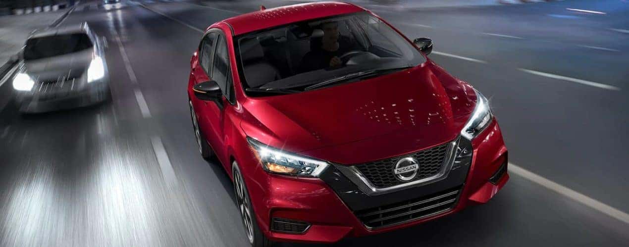 A red 2022 Nissan Versa driving on a highway