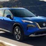 A blue 2022 Nissan Rogue is shown from the front driving on an open road after leaving a Mahomet Nissan dealer.