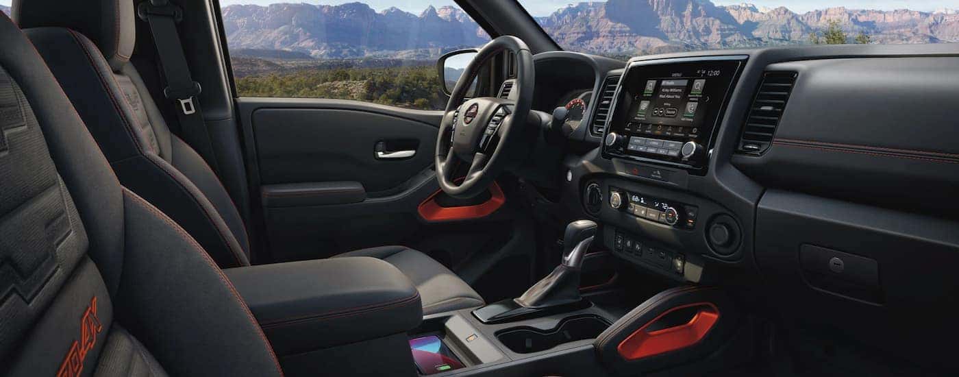 The black interior of a 2022 Nissan Frontier shows the steering wheel and center console.