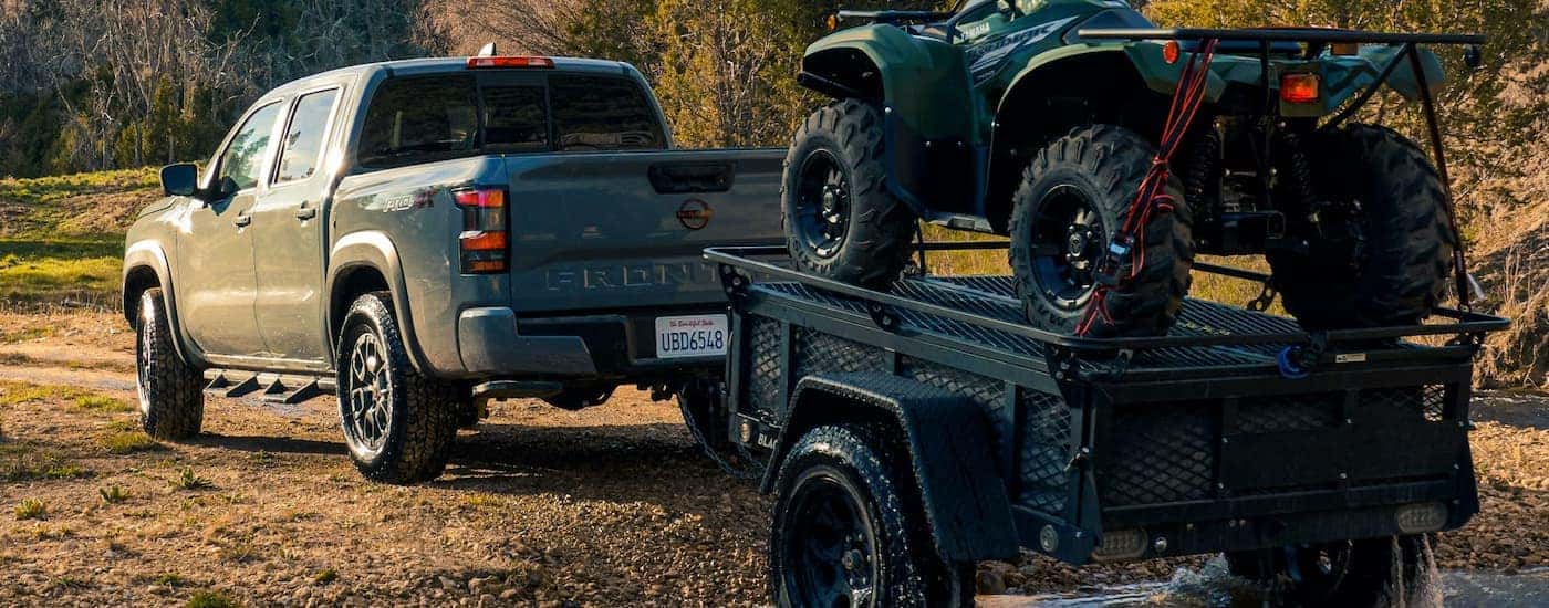 A grey 2022 Nissan Frontier PRO-4X is shown towing an ATV trailer.