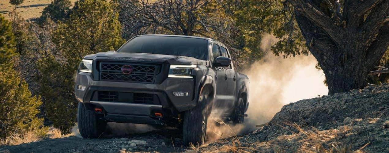 A grey 2022 Nissan Frontier PRO-4X is shown off-roading during a 2022 Nissan Frontier vs 2022 Ford Ranger competition.