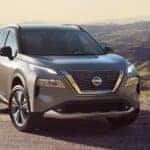 A grey 2022 Nissan Rogue is shown parked in front of a mountain range after leaving a Rantoul Nissan dealership.