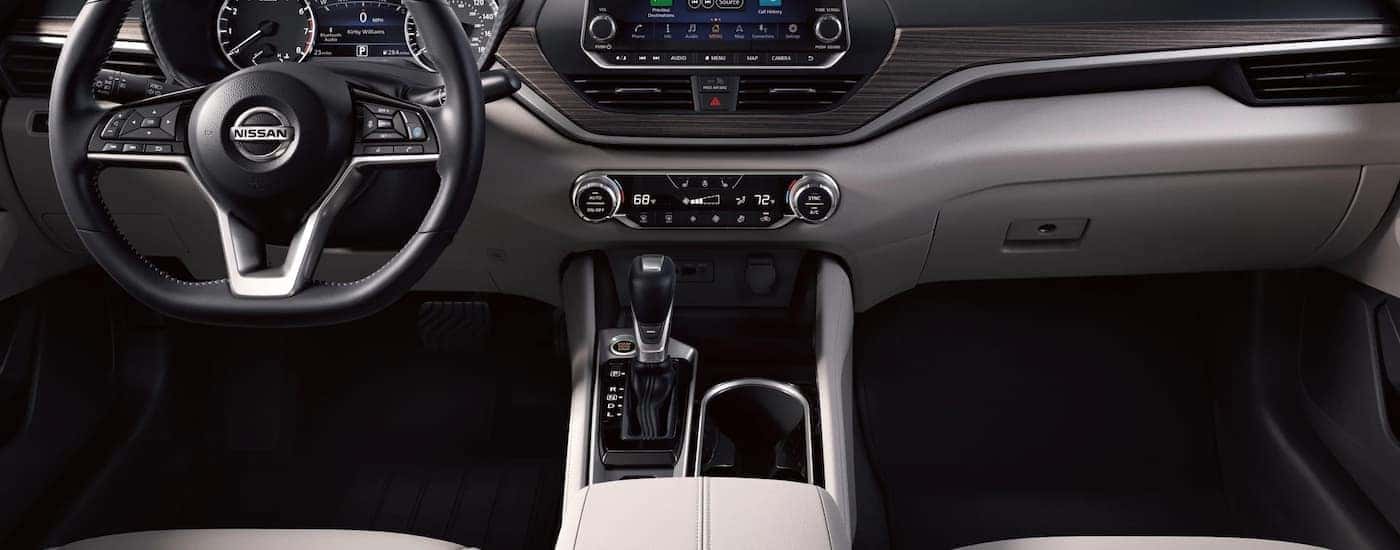 The grey interior of a 2022 Nissan Altima shows the steering wheel and center console.