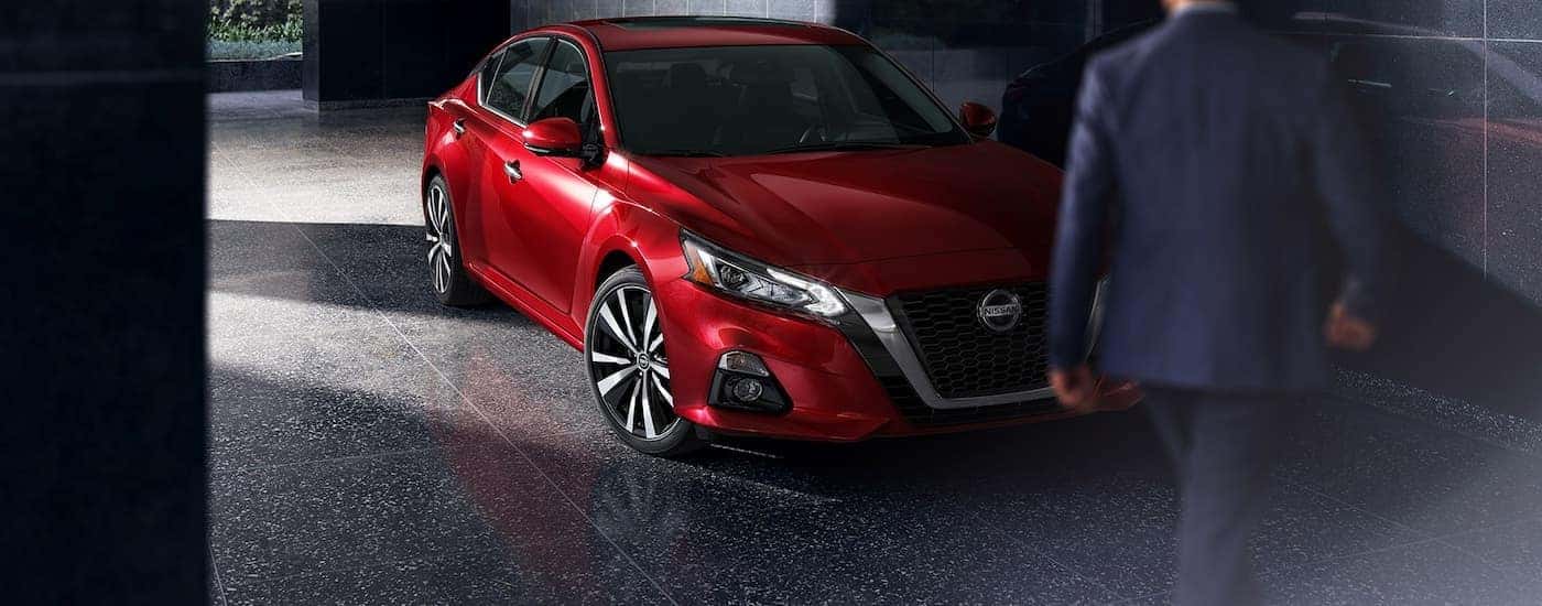 A man is shown walking towards a red 2022 Nissan Altima.