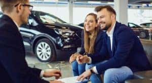 A couple is shown talking to a salesperson at a used car dealership in Champaign, IL.