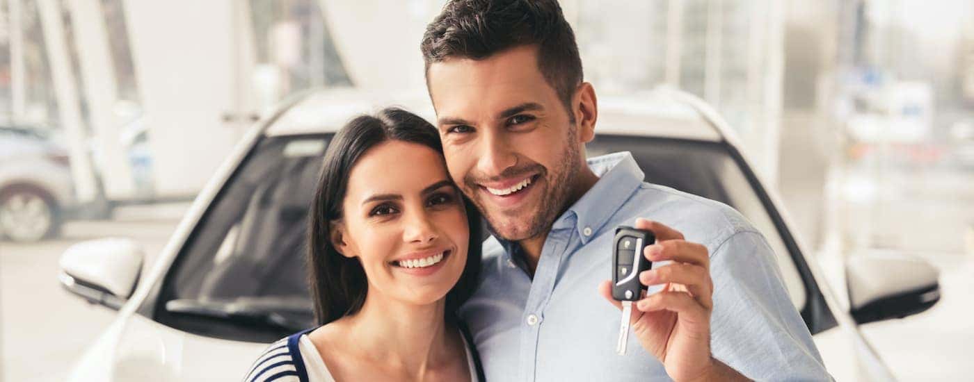 A couple is shown holding up a car key after searching 'Nissan financing.'