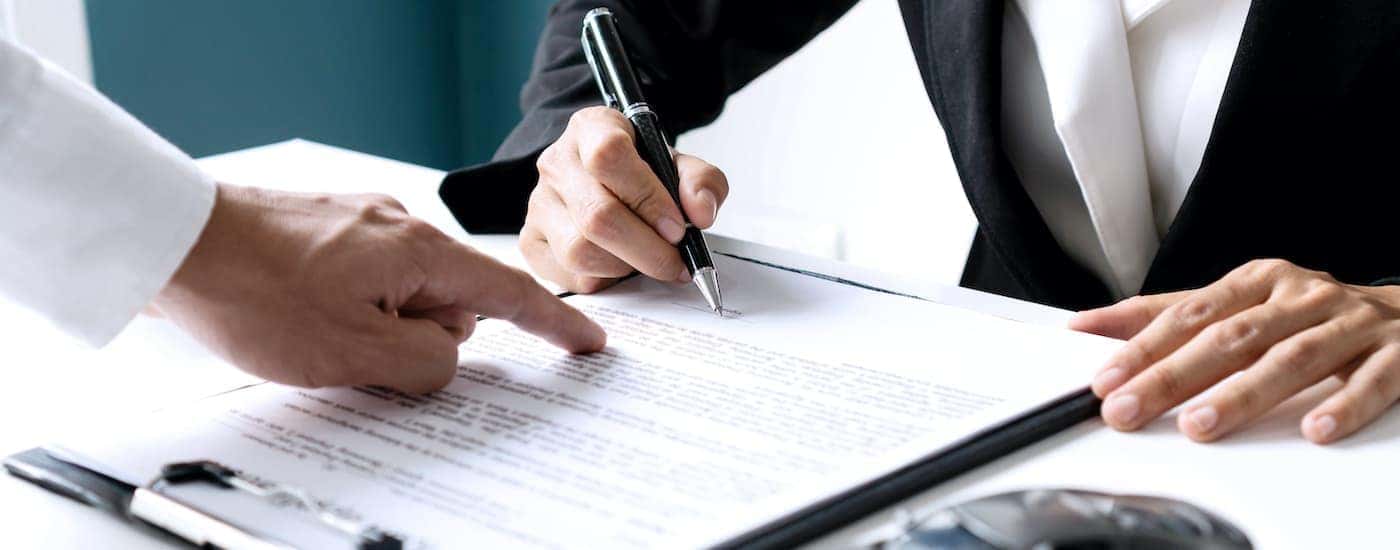 A person is shown filling out finance paperwork.