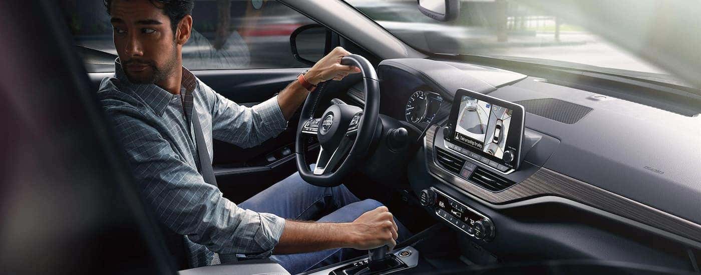 A man is shown backing out of a parking spot in a 2022 Nissan Altima.