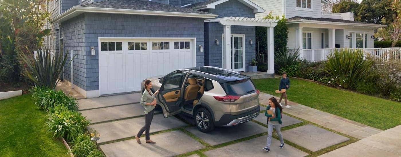 A tan 2022 Nissan Rogue Platinum is shown parked in a driveway.