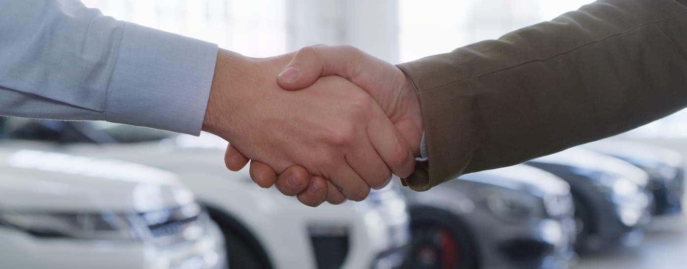 A person is shown shaking hands with a salesperson.