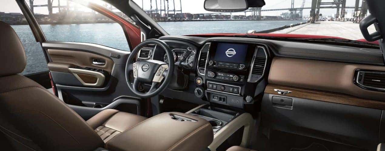 The black interior of a 2023 Nissan Titan shows the steering wheel and infotainment screen.