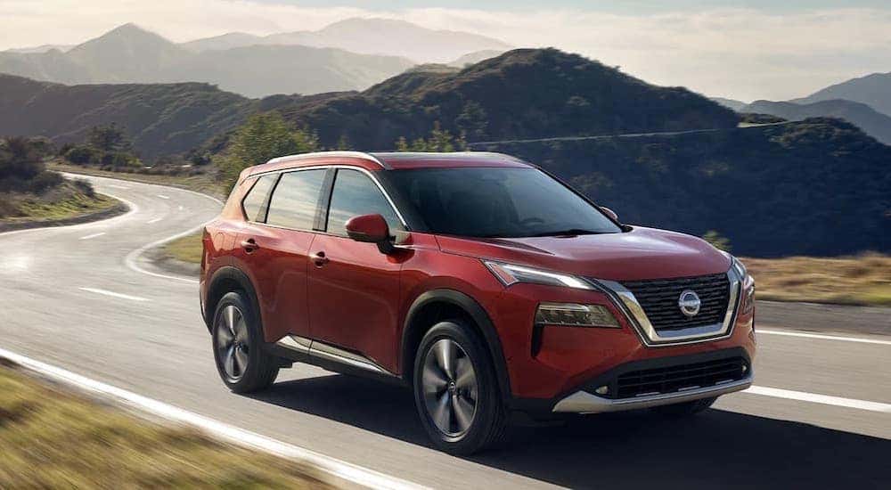 A red 2023 Nissan Rogue is shown from the front at an angle after leaving a dealer that has a Nissan Rogue for sale.