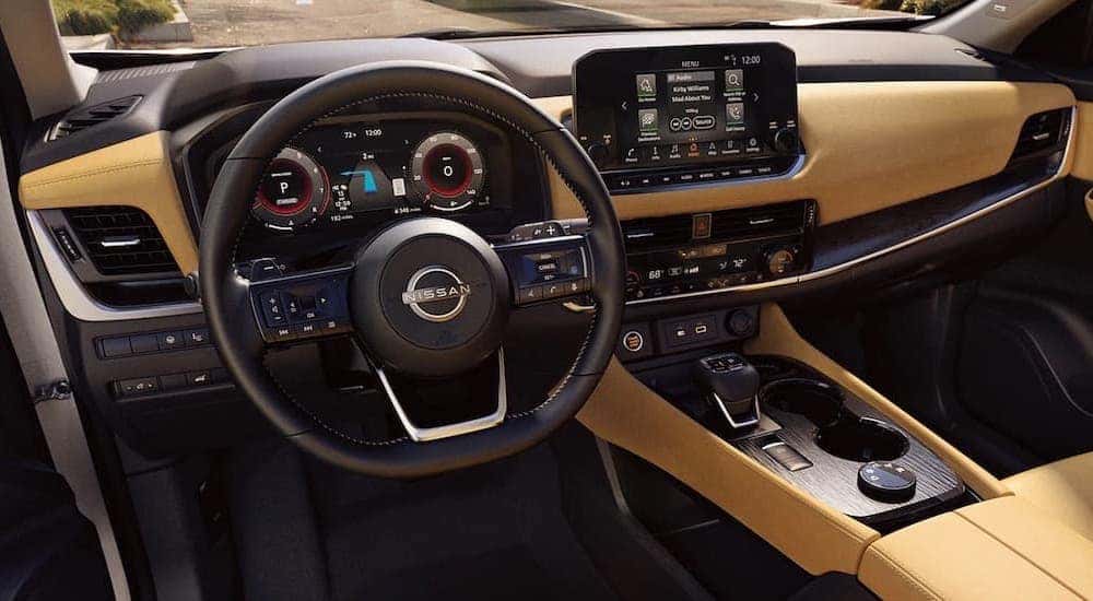 The black and tan interior of a 2023 Nissan Rogue is shown from the driver's seat.