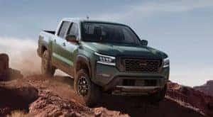 A green 2022 Nissan Frontier is shown off-roading on a dirt trail.