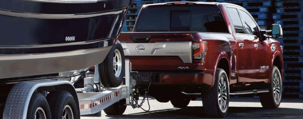 A red 2023 Nissan Titan XD is shown towing a boat.