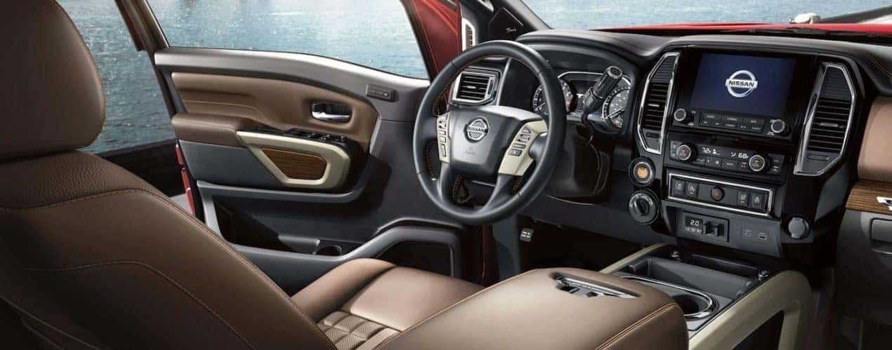 The brown and black interior of a 2023 Nissan Titan XD shows the steering wheel and infotainment screen.