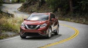 A red 2018 Nissan Murano is shown on a winding road after leaving a used SUV dealer.