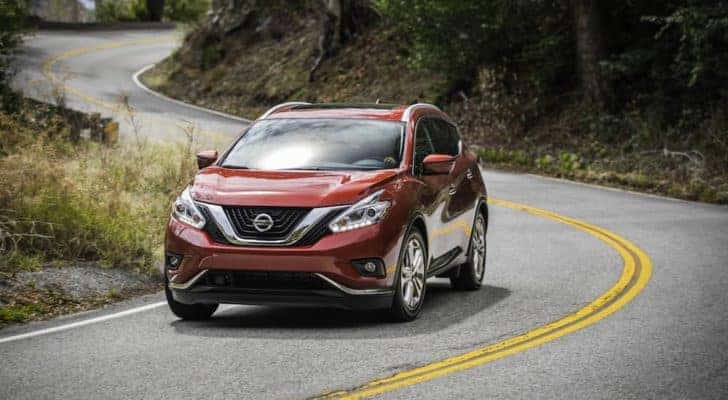 A red 2018 Nissan Murano is shown on a winding road after leaving a used SUV dealer.